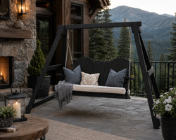 Weather proof black poly A-frame outdoor swing with neutral cushions on a luxury mountain patio overlooking forested peaks.