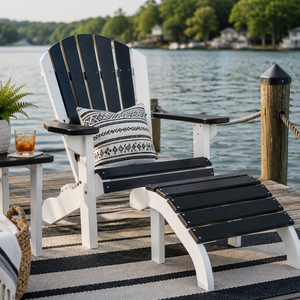 Black and white poly Adirondack chair with matching ottoman on a lakeside dock, styled with a throw pillow for relaxing waterfront views.