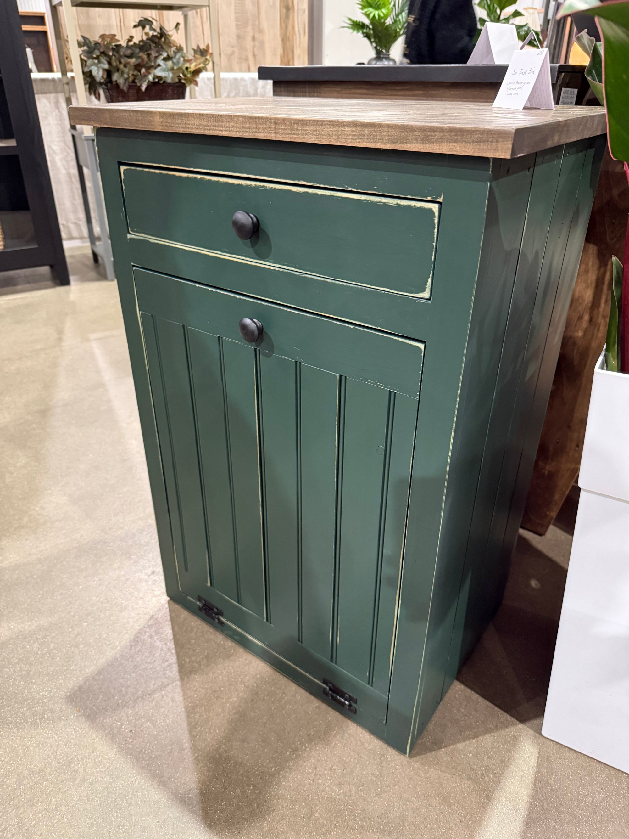 Dark green distressed tilt-out trash bin cabinet with stained countertop