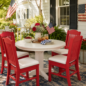 Round white poly outdoor dining table and four red polywood dining chairs on a traditional front porch with patriotic summer décor.