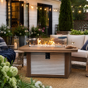 Rectangular poly outdoor fire pit table with glass wind guard in a stylish backyard conversation area with string lights.
