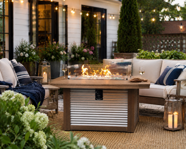 Rectangular poly outdoor fire pit table with glass wind guard in a stylish backyard conversation area with string lights.